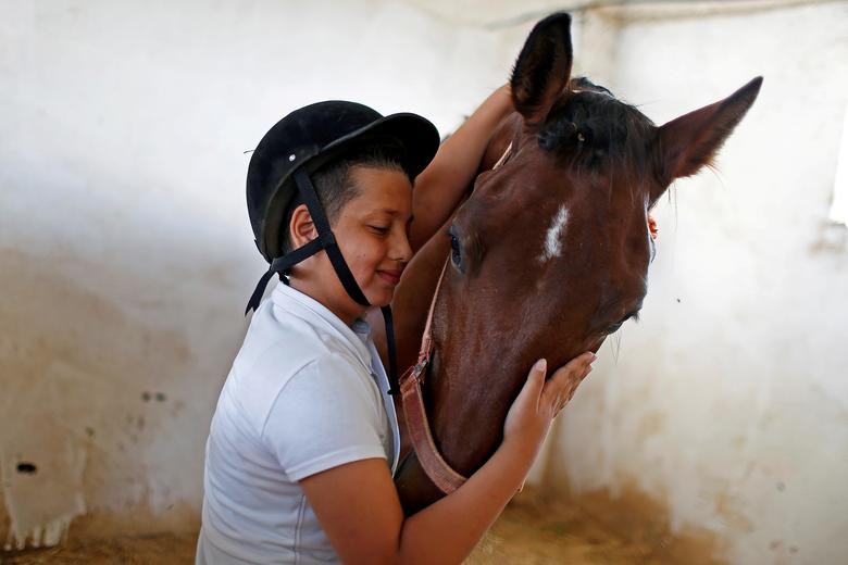 A boy interacts with his horse before competing in a local show jumping that resumed after Palestinians eased the coronavirus restrictions, in Gaza City. REUTERS/Suhaib Salem